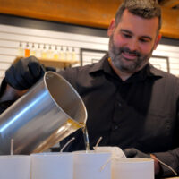 A man pouring candles at Designs by Olivia Grey in Pittston, PA, a popular destination for DIY self-care products in NEPA.