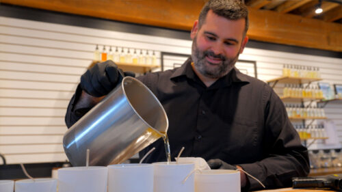 A man pouring candles at Designs by Olivia Grey in Pittston, PA, a popular destination for DIY self-care products in NEPA.