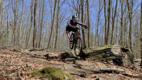 A woman descends a rocky slope along a mountain biking trail at Moon Lake Recreation Area in Hunlock Creek, PA, within Pinchot State Forest.