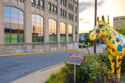 The image shows a yellow, tomato and flower-painted horse statue as part of the Pittston Second Friday Art Walk in Pittston, PA.