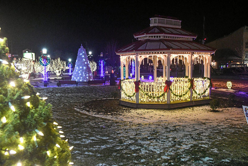 Gazebo and trees adorned with lights, bows, wreaths and decorations. 