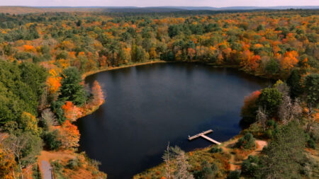 An aerial photo of the pond surrounded by fall foliage at Camp William Penn located within the Delaware State Forest in East Stroudsburg, PA.