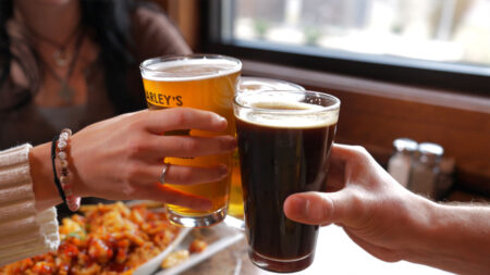 Three patrons clinking pints in celebration at a table at Marley's Brewery and Grille in Bloomsburg, PA.