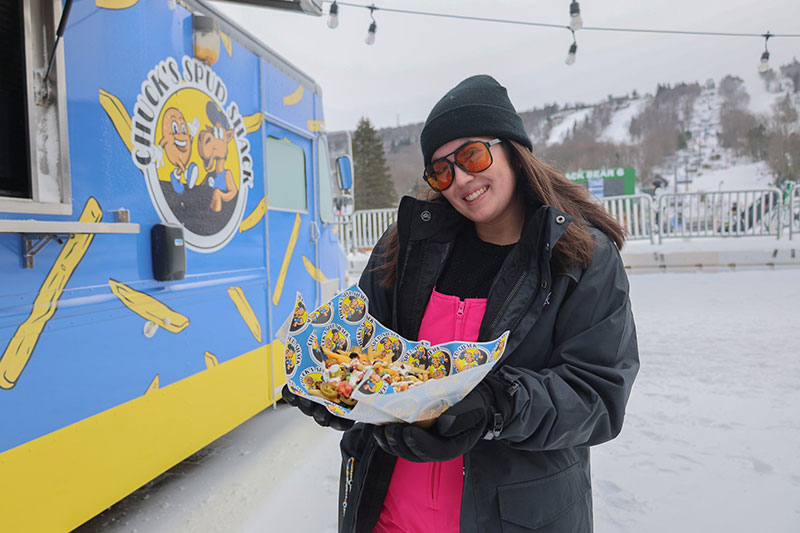 A woman in her ski gear and sunglasses stops by the slope side food truck for a quick snack at Camelback Resort in Tannersville, PA.