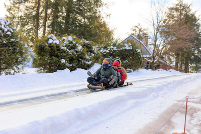 A group of three slide down a hill on a toboggan at the Eagles Mere toboggan slide in Eagles Mere, PA.