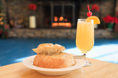 Image of bread bowl and cocktail on table in front of fireplace inside the Winter Garden restaurant at Elk Mountain in Union Dale, PA.
