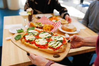 Point of view image taken from behind server as she serves flatbread pizza to a table inside the Winter Garden restaurant at Elk Mountain in Union Dale, PA.