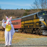 Easter bunny waving at camera while standing next to The Stourbridge Line train in Honesdale, PA.