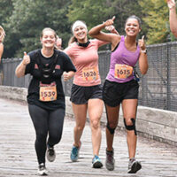 A group of 5 girls smiling and giving a thumbs up during their race in Jim Thorpe, PA.
