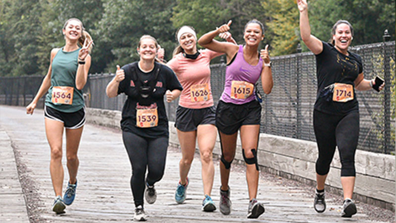 A group of 5 girls smiling and giving a thumbs up during their race in Jim Thorpe, PA.