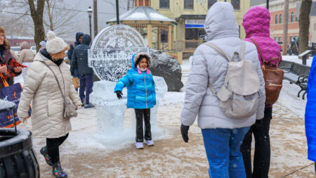 A girl posing and laughing in front of an ice sculpture during Winterfest in Jim Thorpe, PA