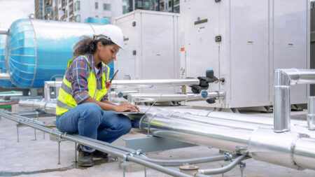 Female engineer inspects and controls the cooling system of a large factory air conditioner