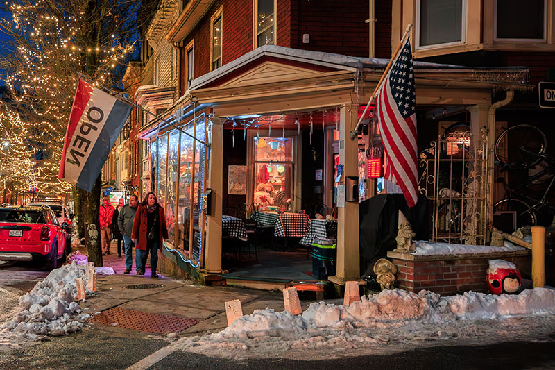A street view of the The Mad Hatter Winery and Smoke House in Jim Thorpe, Pennsylvania, showing the wintery exterior and pedestrians on the sidewalk.