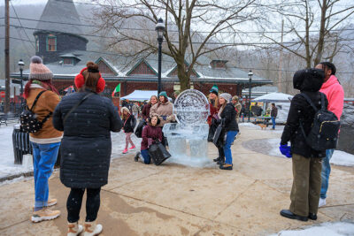A group of people pose in front of an ice sculpture during Winterfest in Jim Thorpe, PA