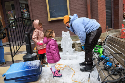 An artist stops to talk to two little girls during Winterfest in Jim Thorpe, PA
