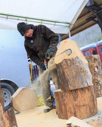 An artist chainsaws through logs during Winterfest in Jim Thorpe, PA
