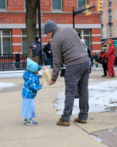 A daughter reaching in the bag of popcorn during Winterfest in Jim Thorpe, PA