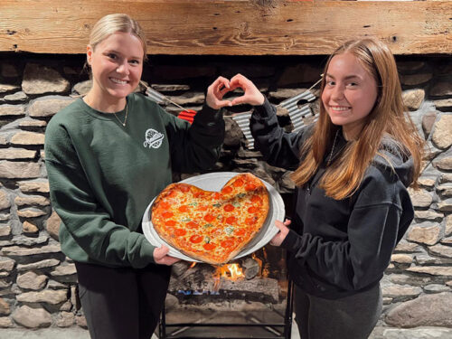 Two staff members holding a heart shaped pizza at Armetta’s Restaurant & Pizzeria in Chinchilla, PA.