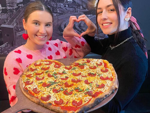 Two staff members holding a heart shaped pizza from Colarusso's Coal Fired Pizza in Dickson City, PA.
