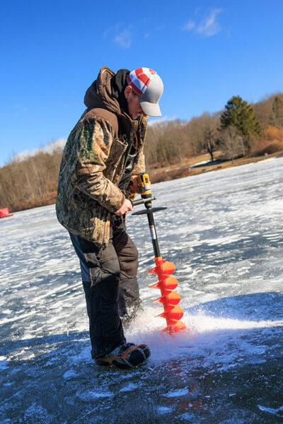 A man drills through the ice during Nanticoke Conservation Club's Ice Fishing Derby at Frances Slocum State Park in Wyoming, PA.