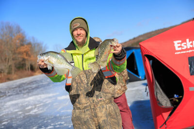 A man holds two fish caught during Nanticoke Conservation Club's Ice Fishing Derby at Frances Slocum State Park in Wyoming, PA.
