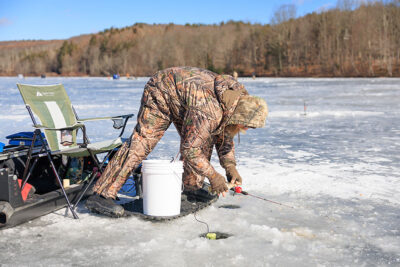 A man unhooks a fish during Nanticoke Conservation Club's Ice Fishing Derby at Frances Slocum State Park in Wyoming, PA.