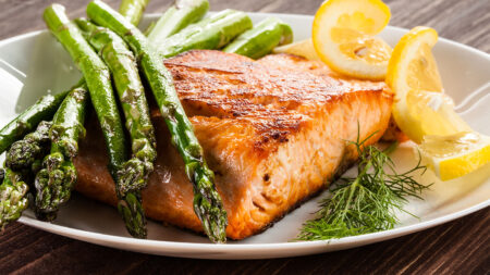 Stock image of a dinner plate of salmon and asparagus with lemon slices.