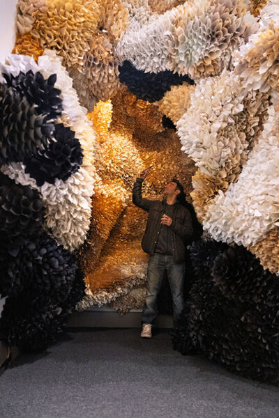 A man snaps a photo from inside a cavernous piece of art that is made up entirely of rolled up pages from a book at the Everhart Museum in Scranton, PA.