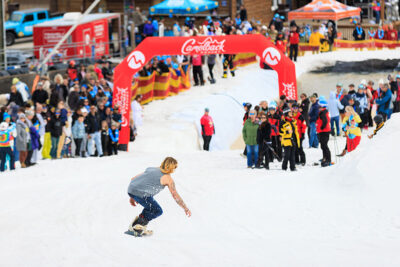 A male snowboarder makes his way down the mountain as he attempts to skim across the pond while spectators cheer him on at Camelback Resort's 20th Pond Skim event in Tannersville, PA.