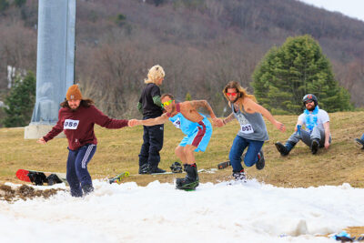 A male snowboarder gets a boost from two fellow participants as he begins his run at Camelback Resort's 20th Pond Skim event in Tannersville, PA.