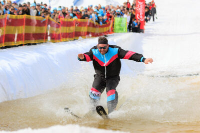 A male skier splashes across a pond while spectators cheer him on at Camelback Resort's 20th Pond Skim event in Tannersville, PA.