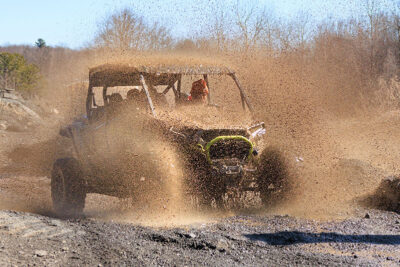 An off-road vehicle splashing through a muddy puddle at Pocono Outdoor Adventure Tours in Long Pond, PA.