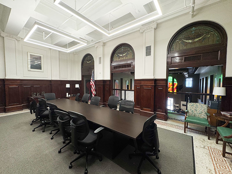 A meeting room with a large table and chairs, featuring three arched windows that overlook the gallery at the Hazleton Art League in Hazleton, PA.