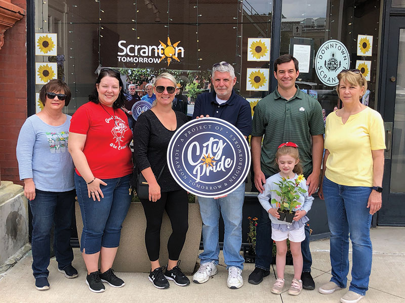 A group representing Scranton City Pride, Neighborworks and Scranton Tomorrow pose in front of the Scranton Tomorrow office.