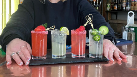 A women's hands setting down a colorful flight of margaritas from Armetta's Restaurant in Chinchilla, PA.