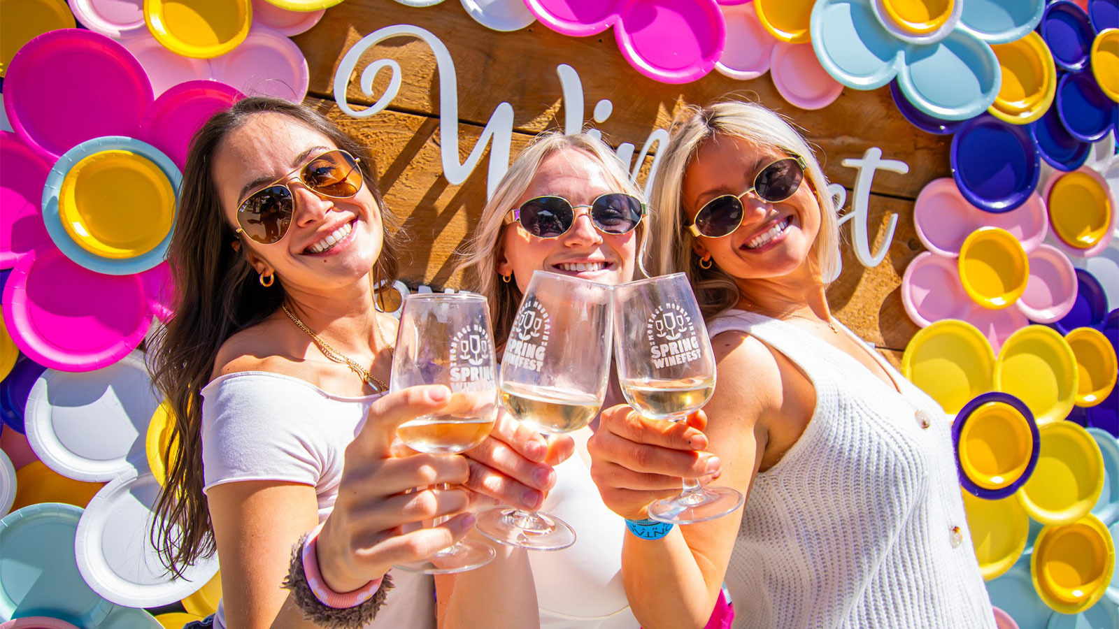 Women holding wine glasses and posing in front of a photo-op at the Spring Wine Fest at Montage Mountain Resorts in Scranton, PA.