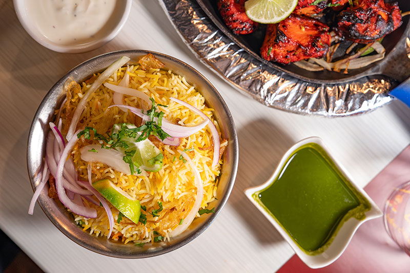 An overhead photo of a table with yellow rice next to a side of green sauce and white sauce from Zupadi Indian Restaurant in Kingston, PA.