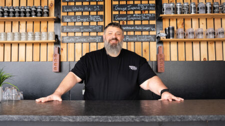 A man with a gray beard stands behind the bar at Groove Brewing in Scranton.