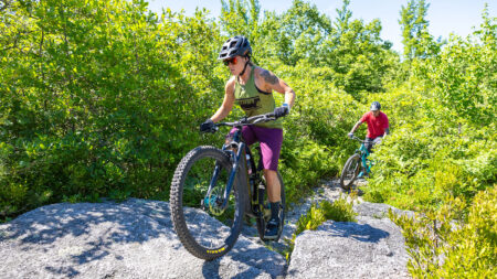 Two mountain bikers make their way up rocky terrain surrounded by shrubs at Dick and Nancy Eales Preserve in Moosic, PA.