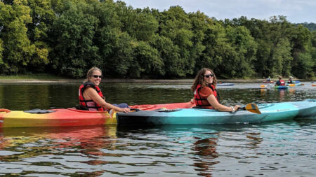 Two women in kayaks pose for a photo while paddling down the Susquehanna River.