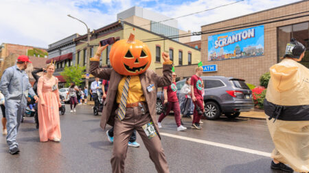 A woman dressed as Dwight Schrute with a carved pumpkin over her head poses for the camera during The Office 5k in Scranton, PA.