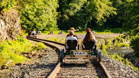 Four people ride a 4-seat tandem electric railbike at Pennsylvania Rail Bike in Hawley, PA.