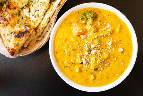 A bowl of yellow chicken korma with naan