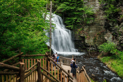 Tourists standing in front of one of the 8 waterfalls at Bushkill Falls in Bushkill, PA.