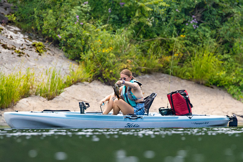 A woman prepares to release a smallmouth bass while fishing from a kayak on the Delaware River in Milford, PA.
