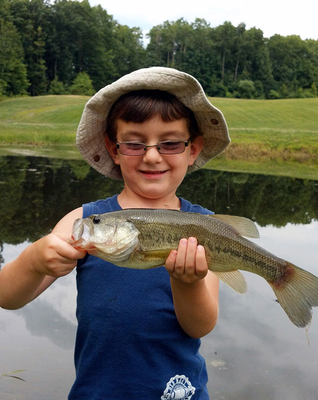 A young fisherman proudly shows off his catch from a pond in Harding, PA.