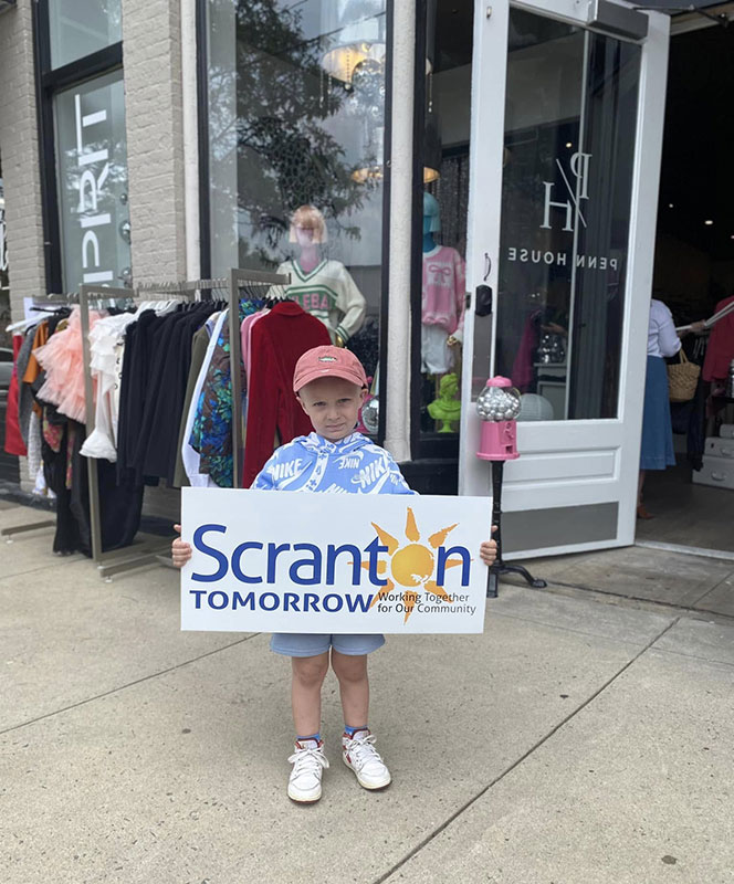 A child poses with a sign that reads "Scranton Tomorrow" outside a shop in Downtown Scranton, PA.