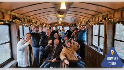 A group raises their beer glasses for a photo while on a vintage train car in York, PA.