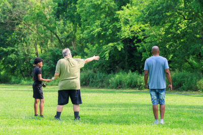 An instructor teaches a young boy how to cast a fly rod during the 2025 River of the Year celebration at Minisink Park in East Stroudsburg, PA.