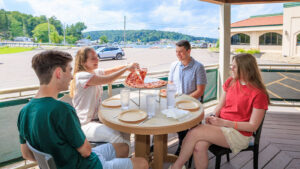 Four people sitting at a table sharing pizza at Grotto Pizza in Harveys Lake, PA.